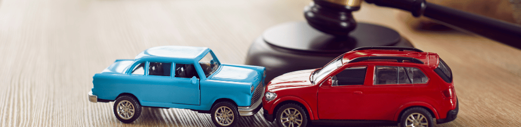 A blue toy truck, and a red toy car, in an accident on a lawyer's desk.