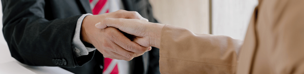 Two people in sport jackets shaking hands.