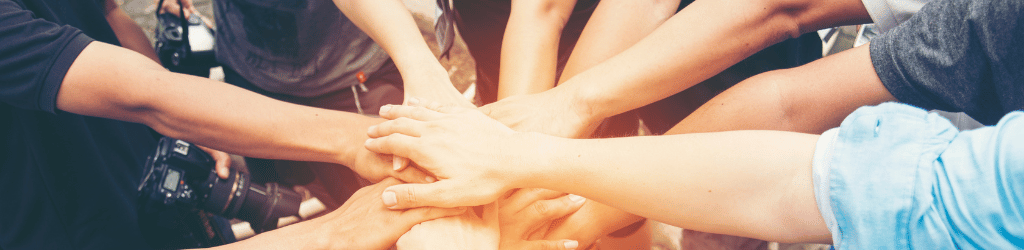 Ten people putting their hands together to cheer.