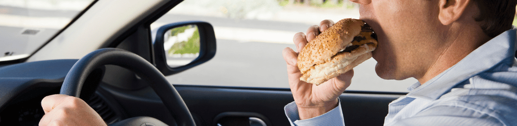 Man eating cheeseburger while driving.