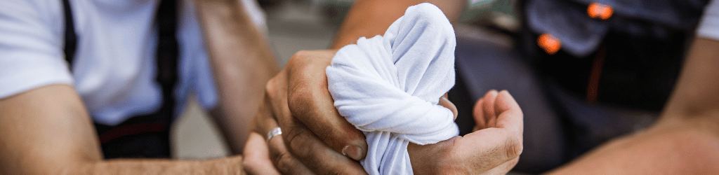 Man with injured thumb getting first aid treatment.