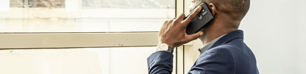 A young black man in a suit making an important phone call.