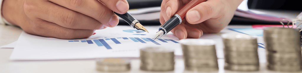 Close Up of Person with Stacked Coins Analyzing Graphs